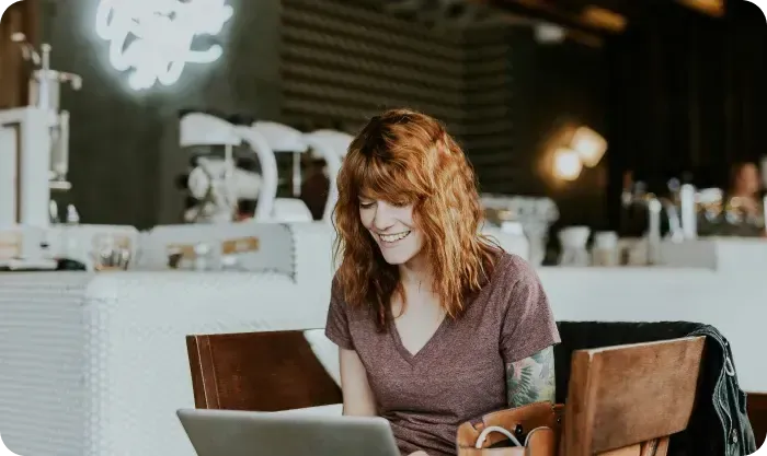 Smiling woman working on a laptop at a café table