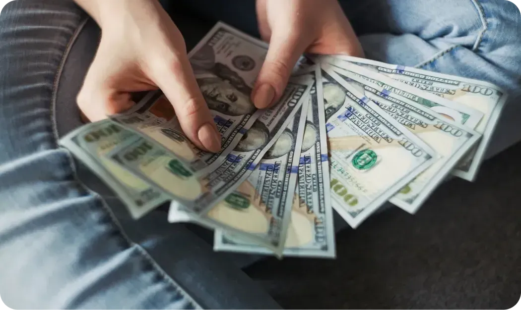 Hands holding a fan of 100-dollar bills