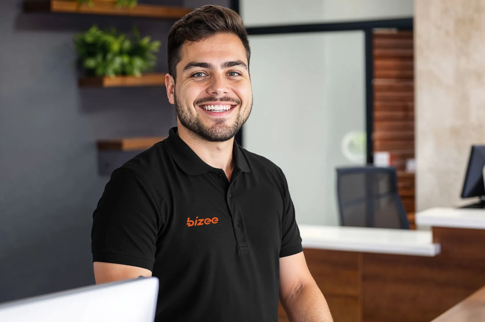 Smiling Bizee team member in a black polo at a reception desk