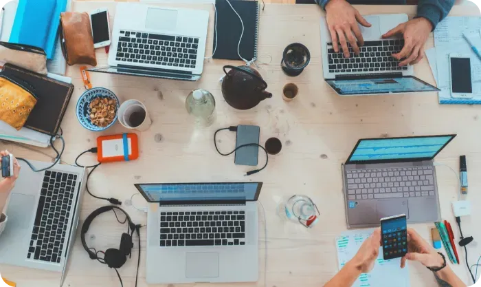 Overhead view of laptops, phones and coffee on a shared work table