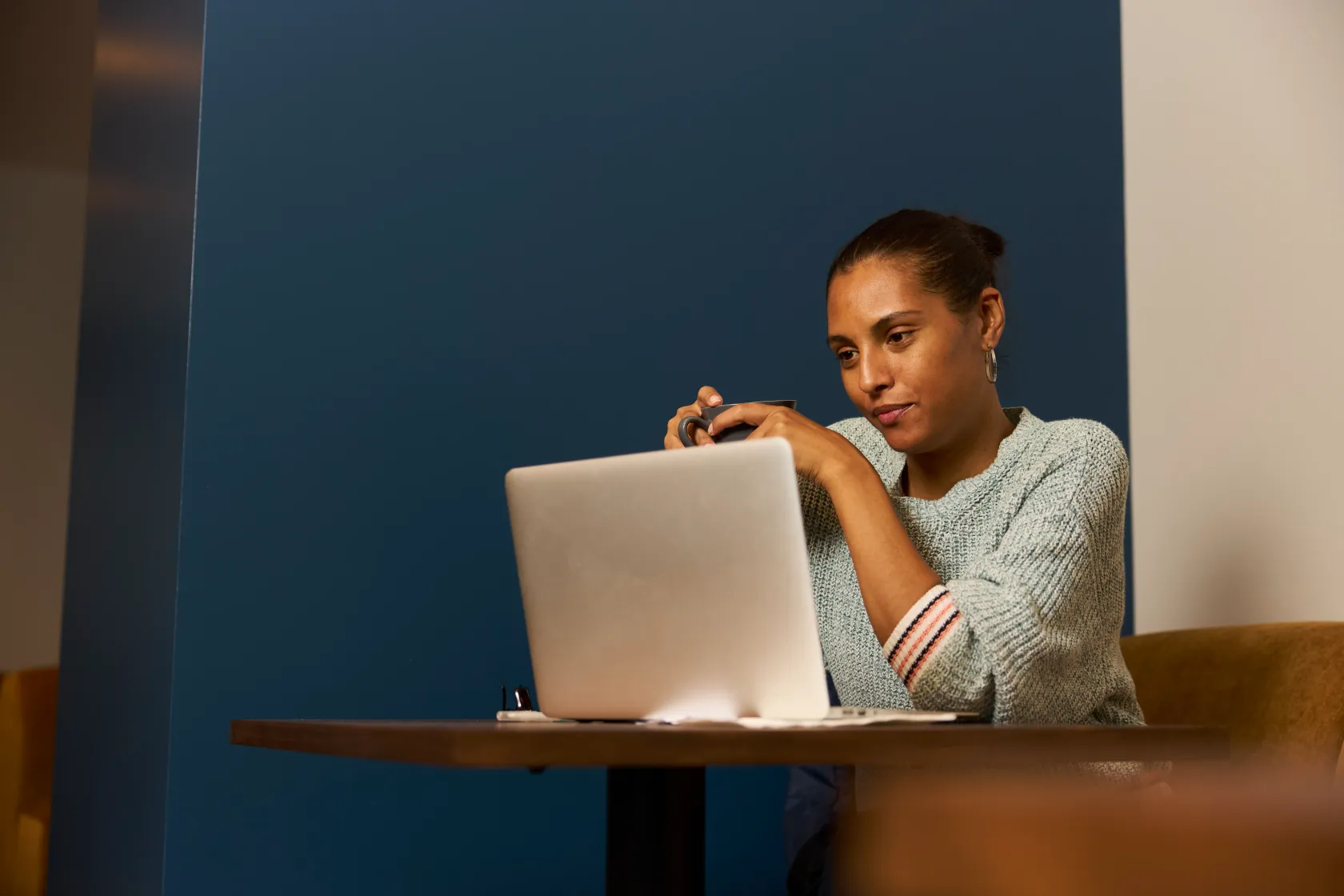Women holding a pen working on her laptop at cafe.