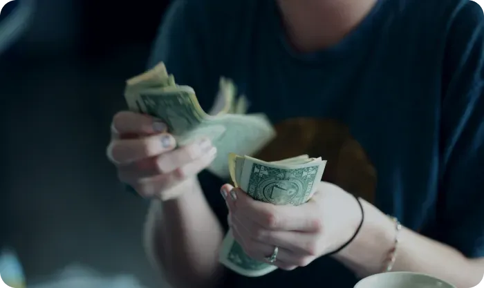 Hands counting a stack of dollar bills