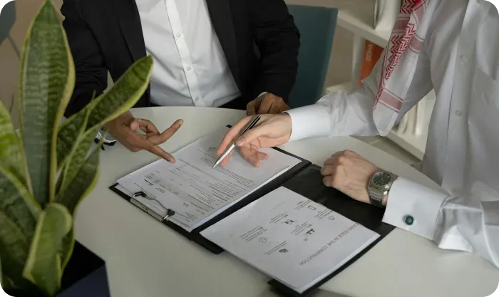 Two people reviewing contract papers on clipboards at a table, one pointing with a pen