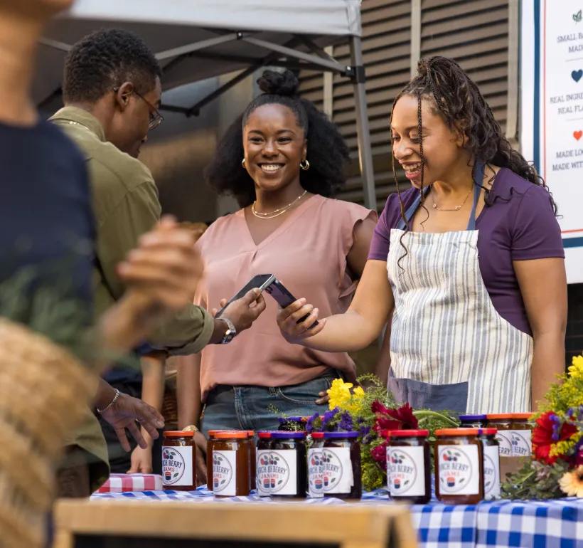 Three small-business owners talking at a market stall selling Birch Berry Jams