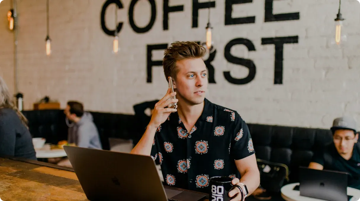 Man On The Phone With Mug In Another Hand
