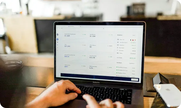 Person typing on a laptop showing a financial dashboard with revenue figures