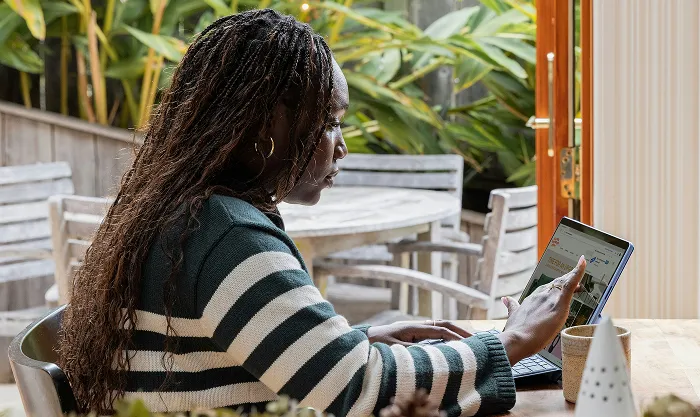 Woman in a striped sweater using a tablet at an outdoor patio table