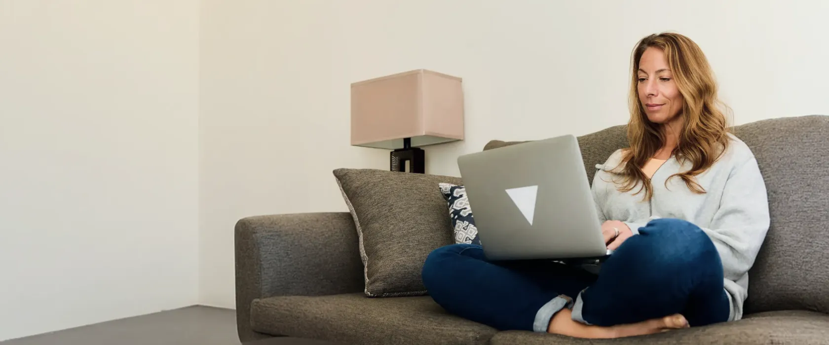 Woman working on her laptop while sitting on a sofa