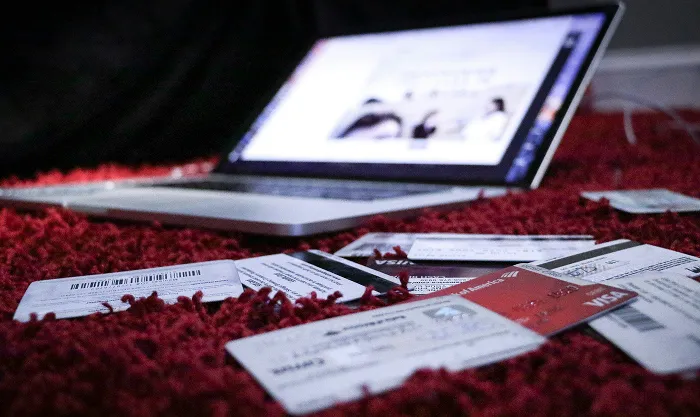 Laptop on a red rug surrounded by scattered credit and debit cards