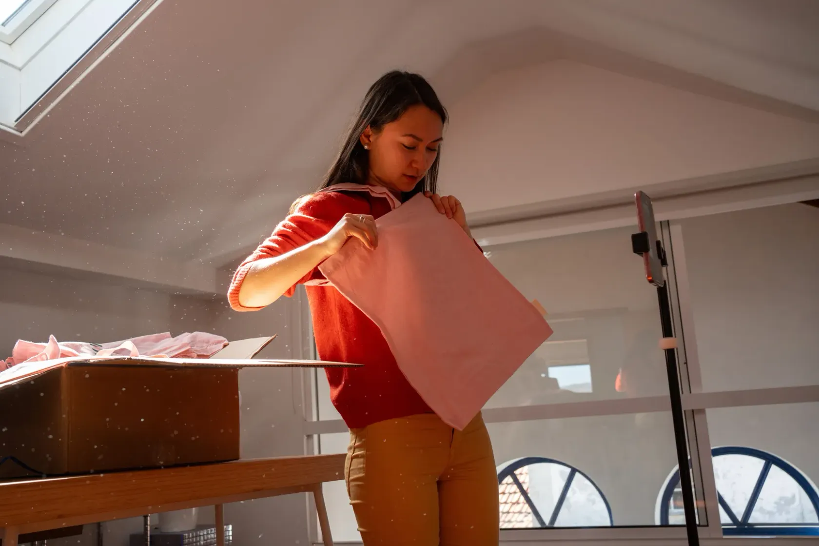 Woman packing branded tote bag under soft studio light.