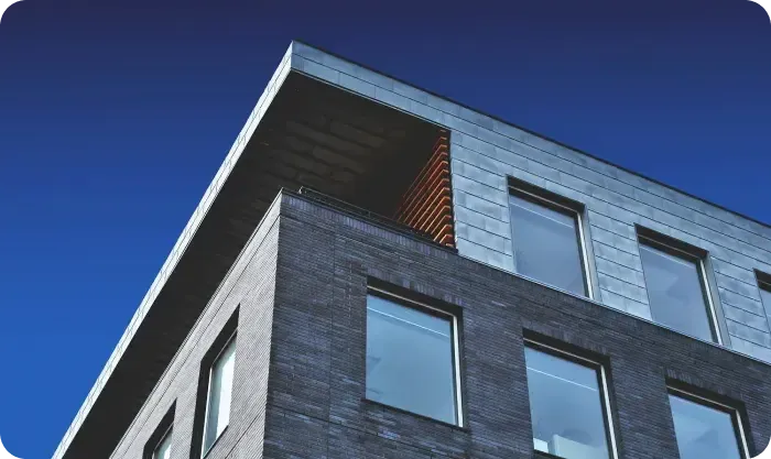 Corner of a dark brick office building with rows of windows against a deep blue sky