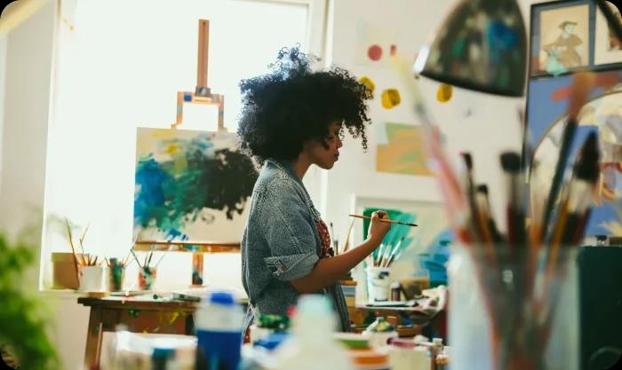 A female artist painting on a canvas in her art studio.