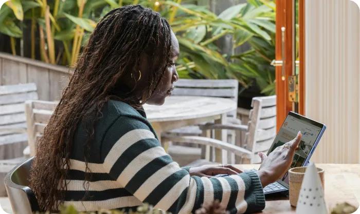 Woman in a striped T-shirt working at a computer with a touchscreen in the canteen