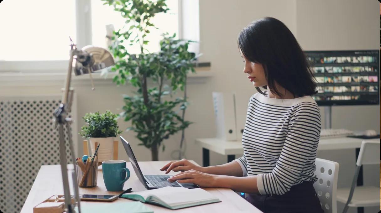 Woman in a striped T-shirt working at a computer in the office