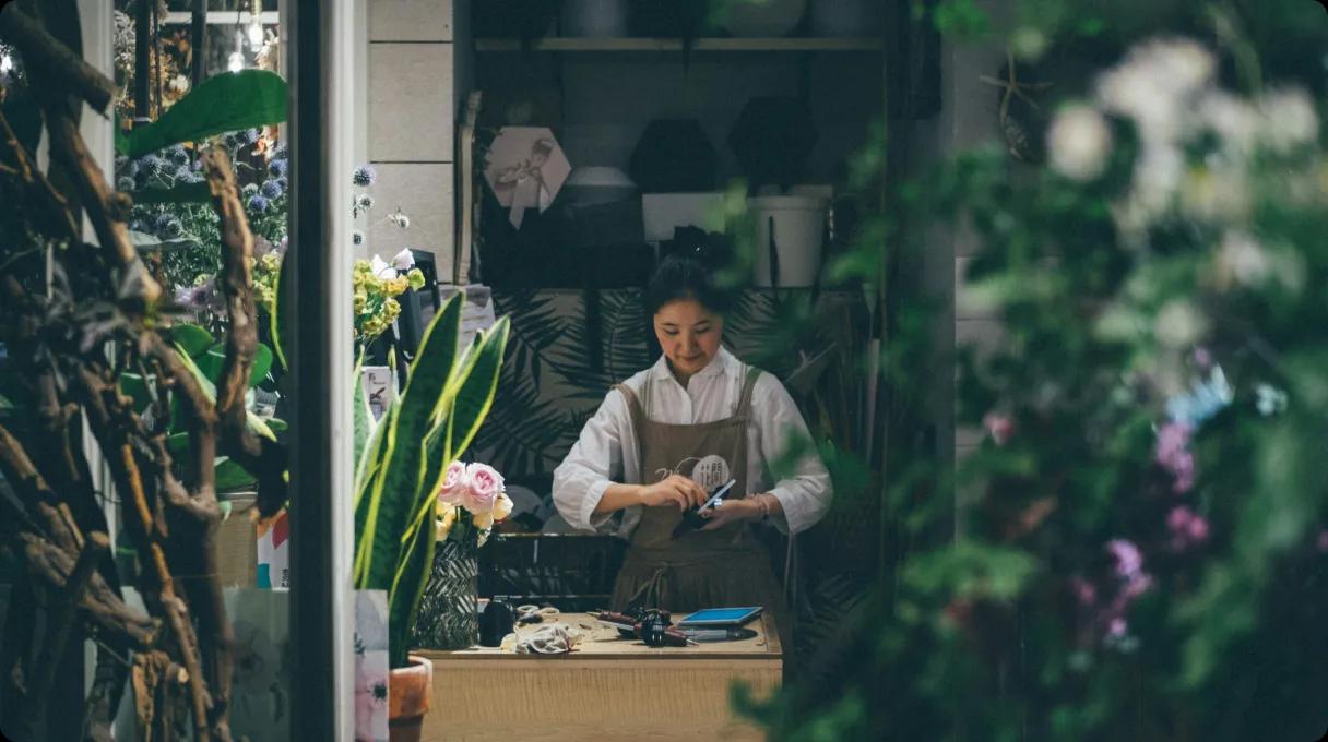 A woman in an apron carefully arranging flowers for a beautiful floral display.