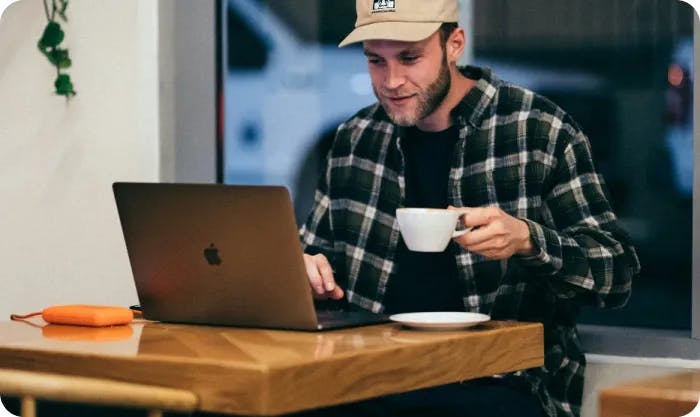 Man drinking a coffee while working on his laptop