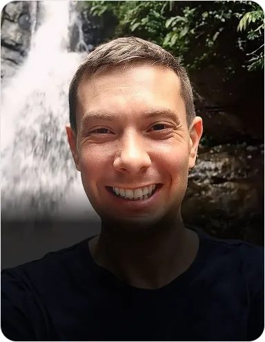 Adam Riemer is on the waterfall landscape, smiling at the camera.