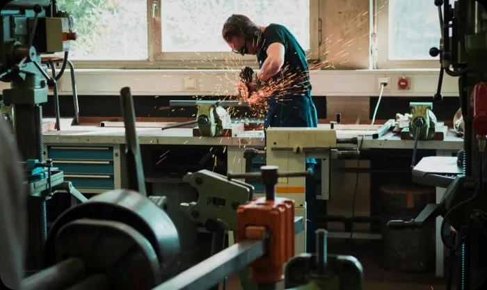 A man diligently operates a machine in a well-equipped workshop, showcasing his skills and focus on the task at hand.