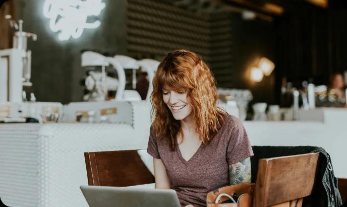 A woman sitting and working on a laptop and smiling