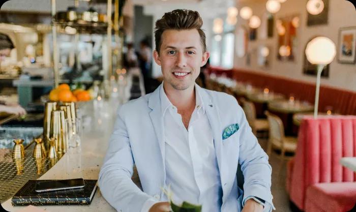 A man in a suit seated at a bar, exuding a professional demeanor in a relaxed social setting.