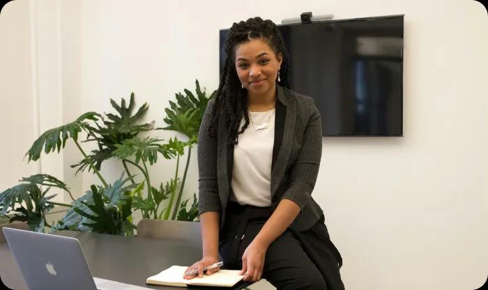 A woman smiling holding a pen and some papers.