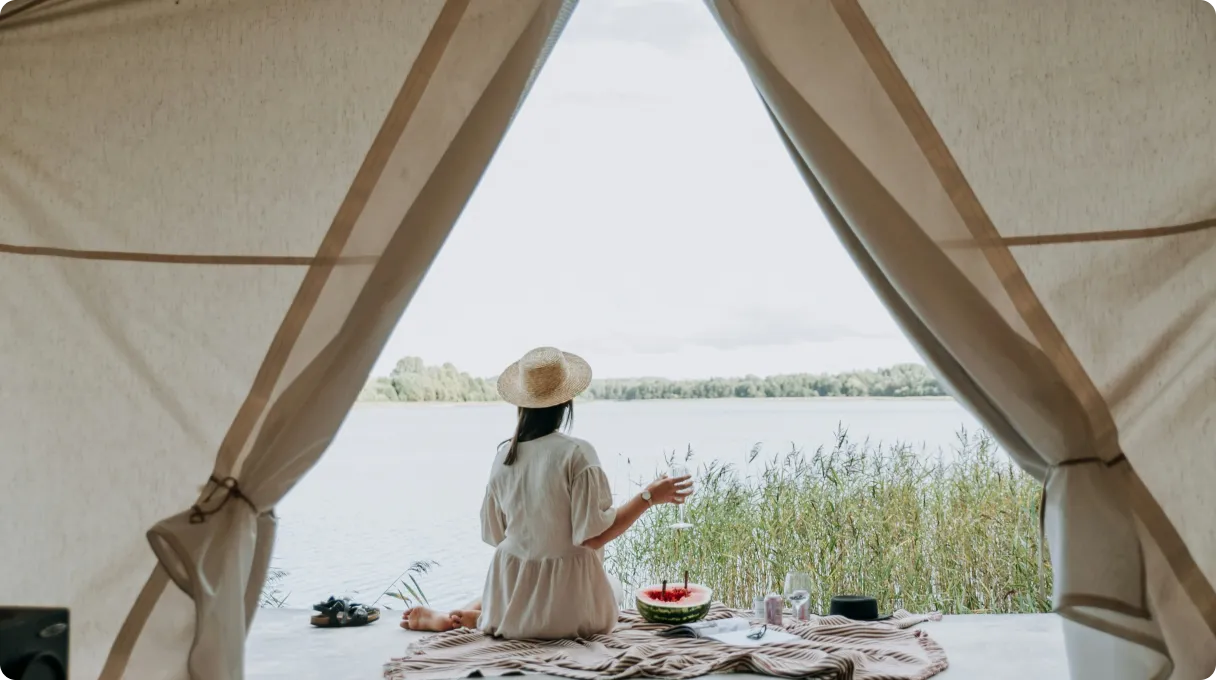 Woman sitting outside a tent on a lake shore