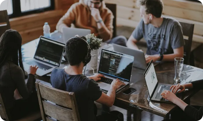 Group of people sitting by table with laptops