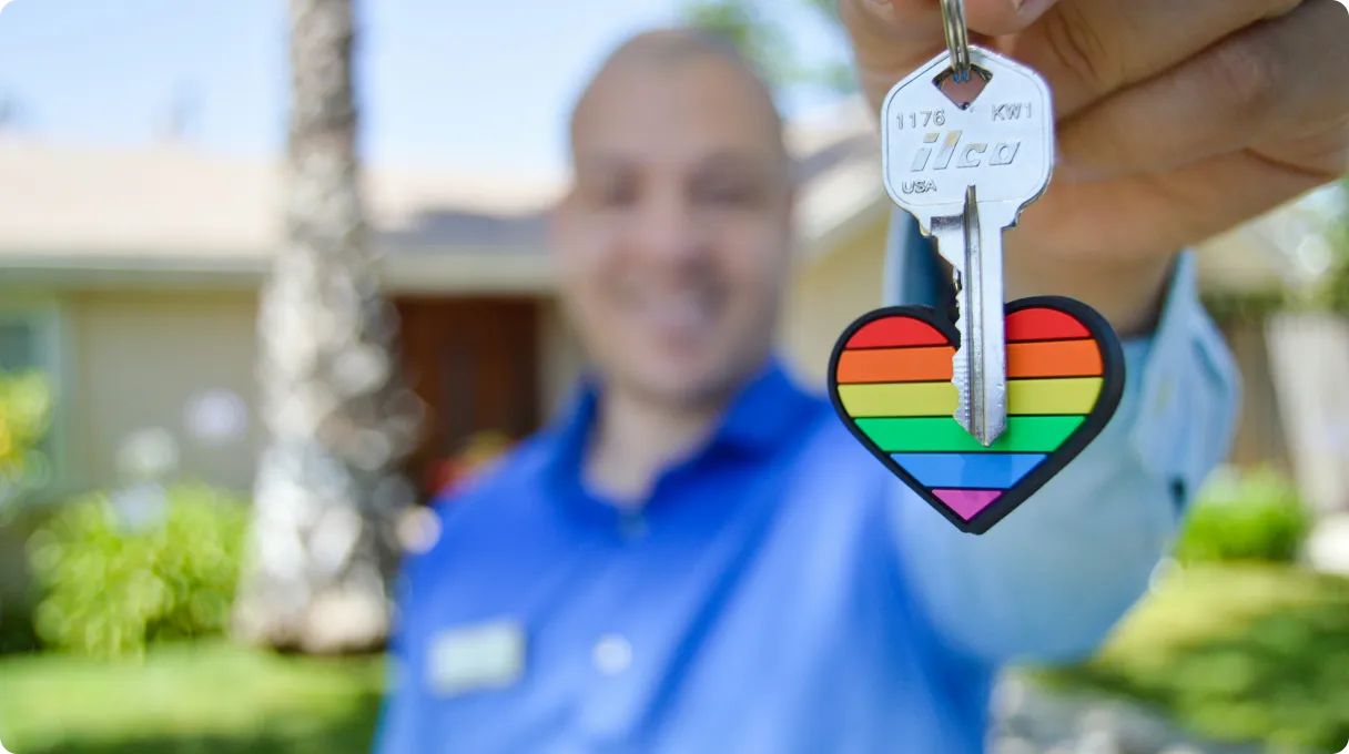 Man holding a key with rainbow heart trinket