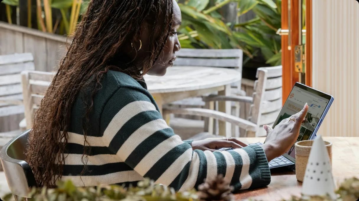 WOmen sitting and typing on laptop with touchscreen