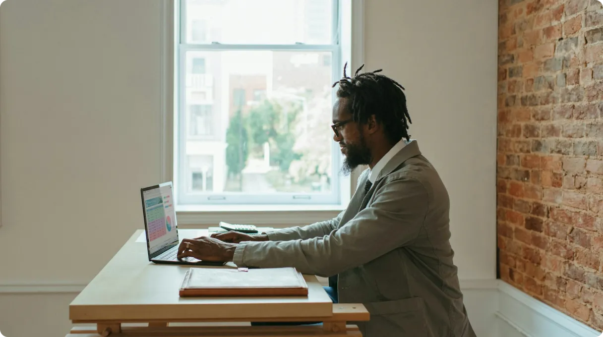 A person sitting at a desk with a laptop and papers