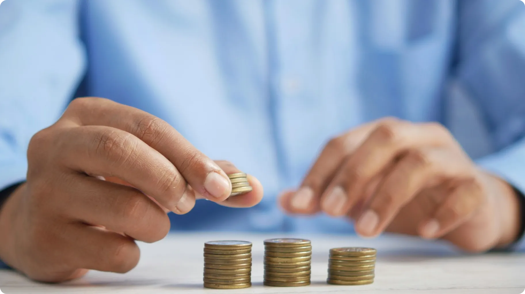 A-person-in-a-blue-shirt-carefully-stacking-coins-into-small-piles-on-a-table-symbolizing-saving-budgeting-or-financial-planning