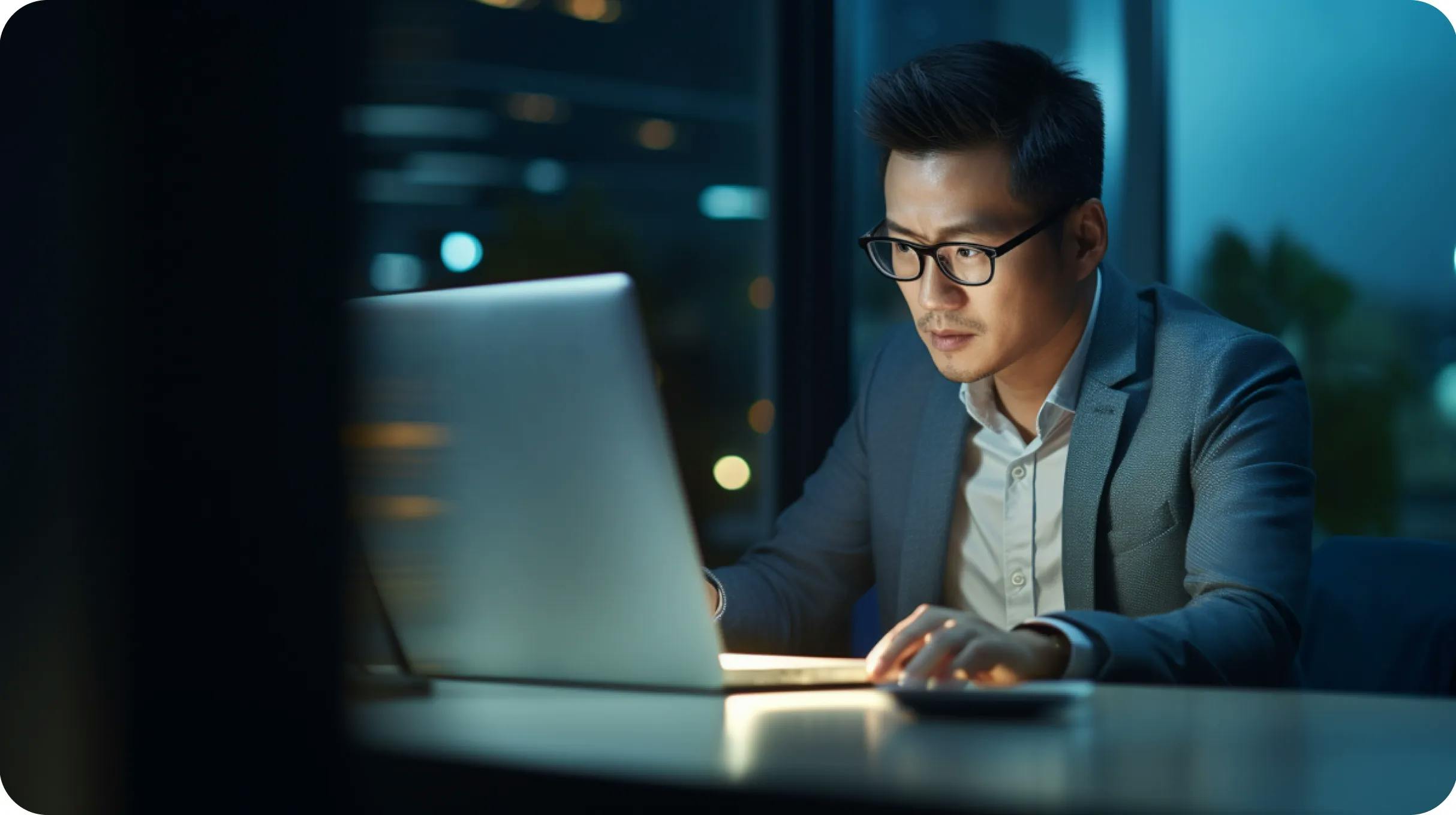 Asian man working at night in an office on a laptop