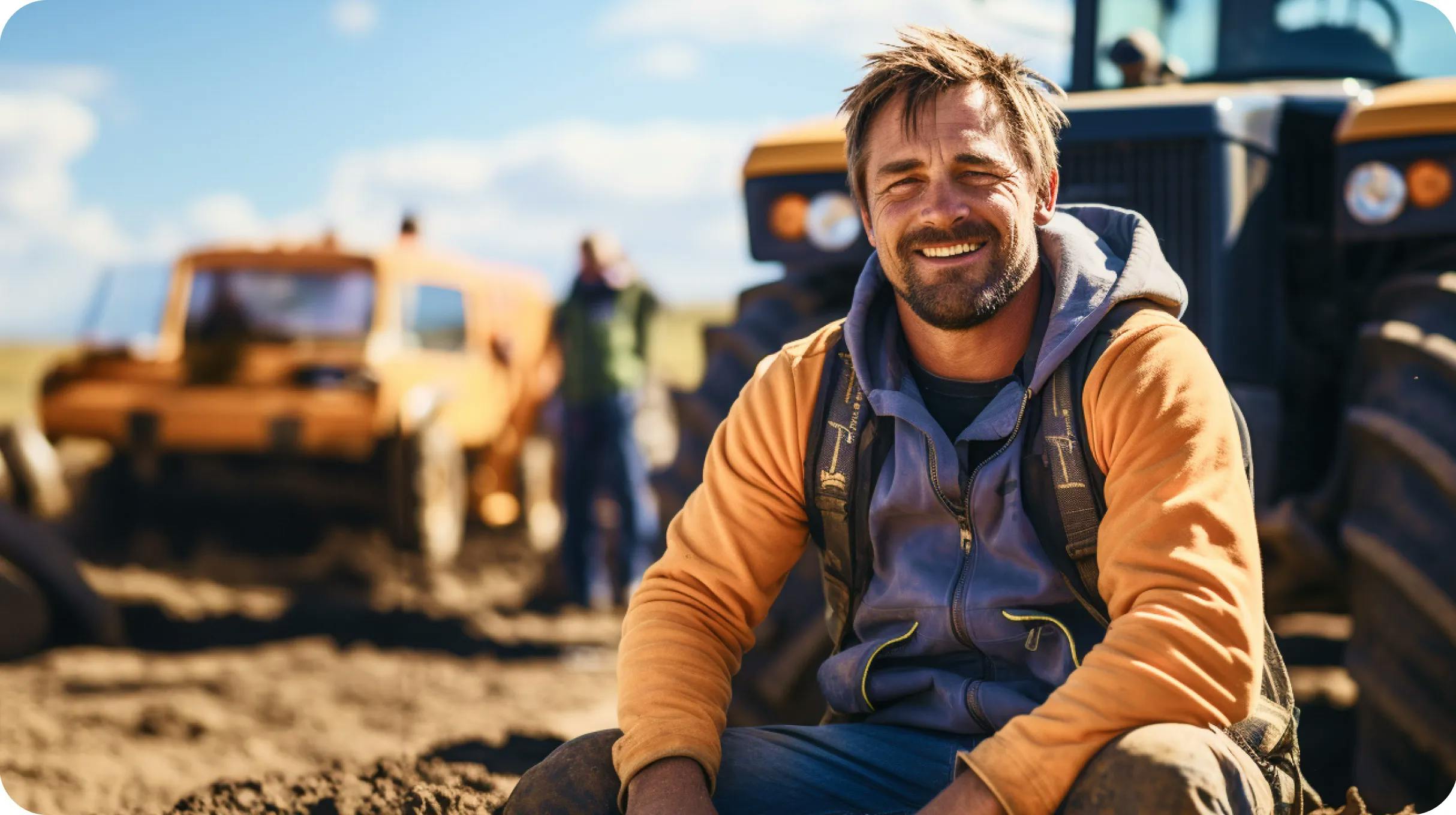 A construction worker sitting on a ground, with heavy equipment in the background
