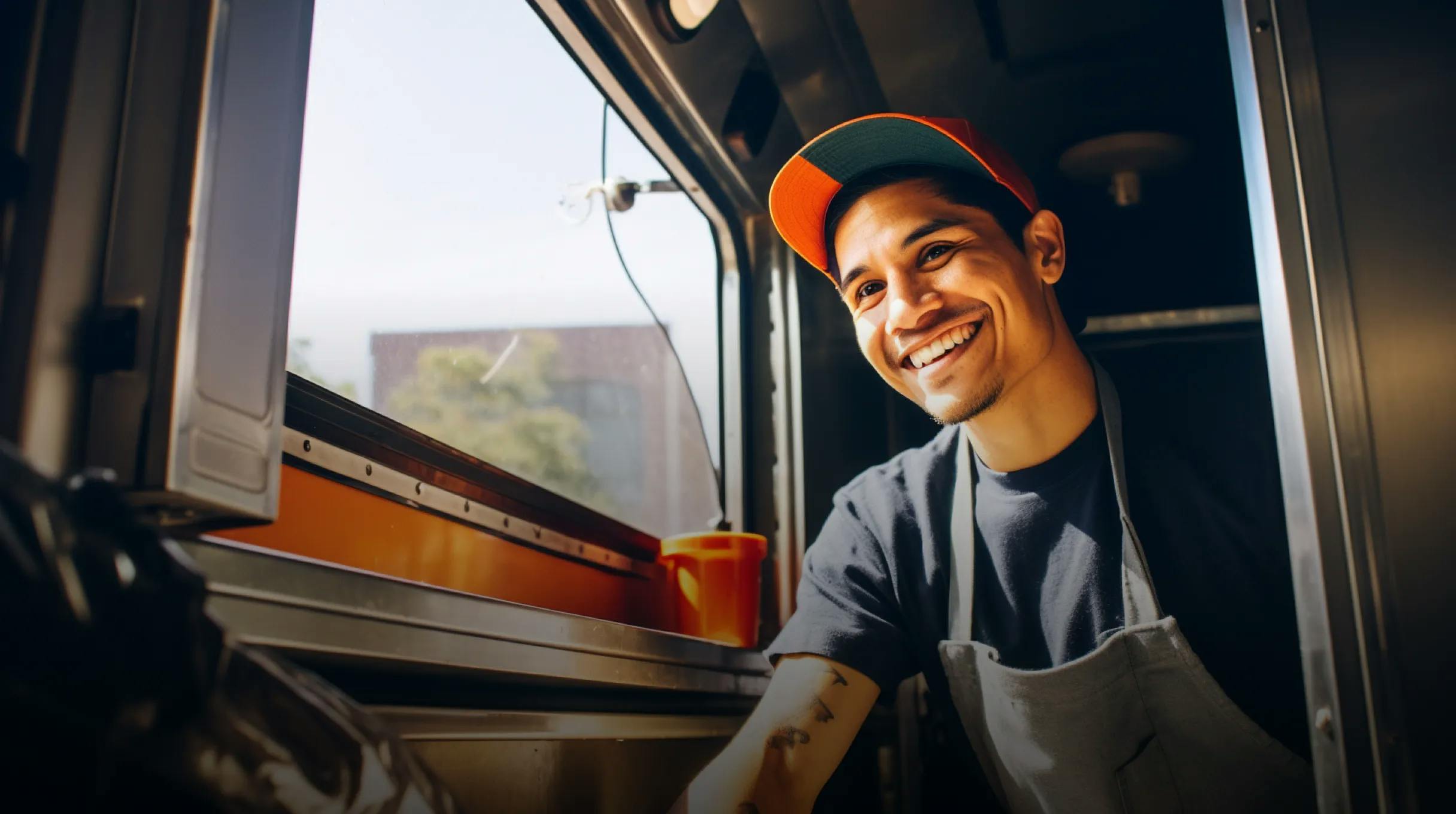 A young man sitting in a foodtruck serving food