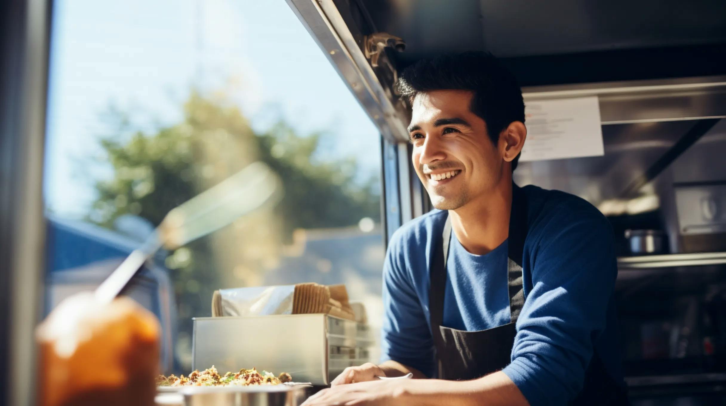 A man with a cheerful expression is seen working in a food truck, radiating happiness and dedication.