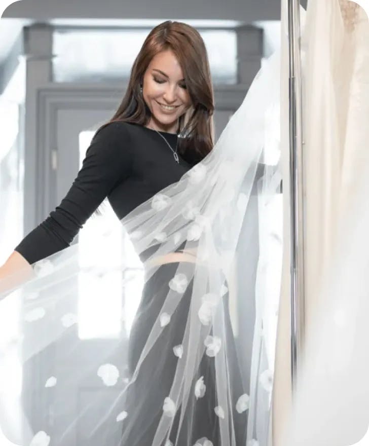 Marina Andriichenko holding a gown and smiling.