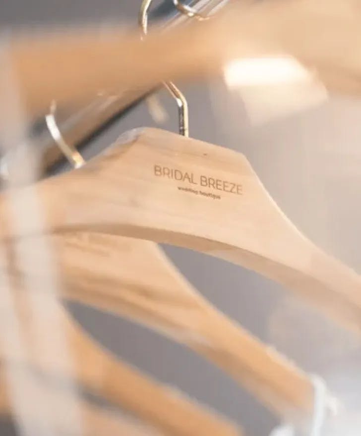 Wooden clothing hangers with the Bridal Breeze logo.