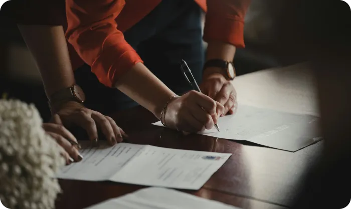 Person in orange long sleeve shirt writing on white paper