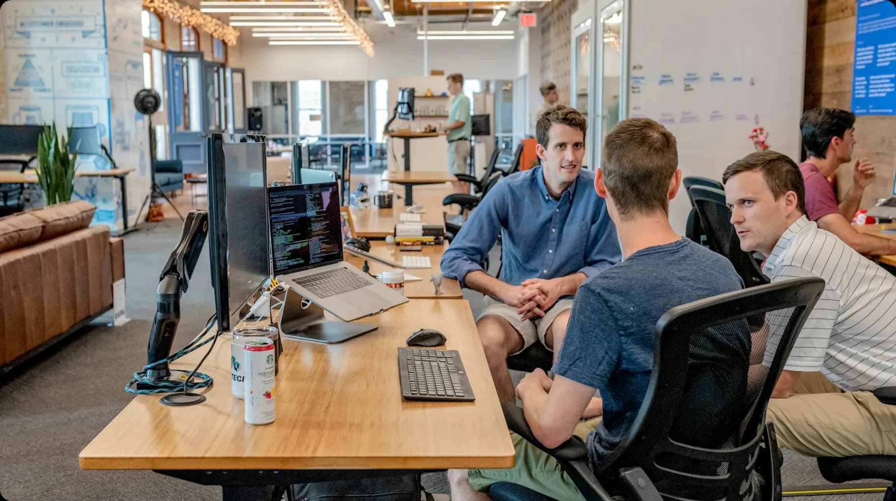 three-men-sitting-on-chair-beside-tables-with-computers