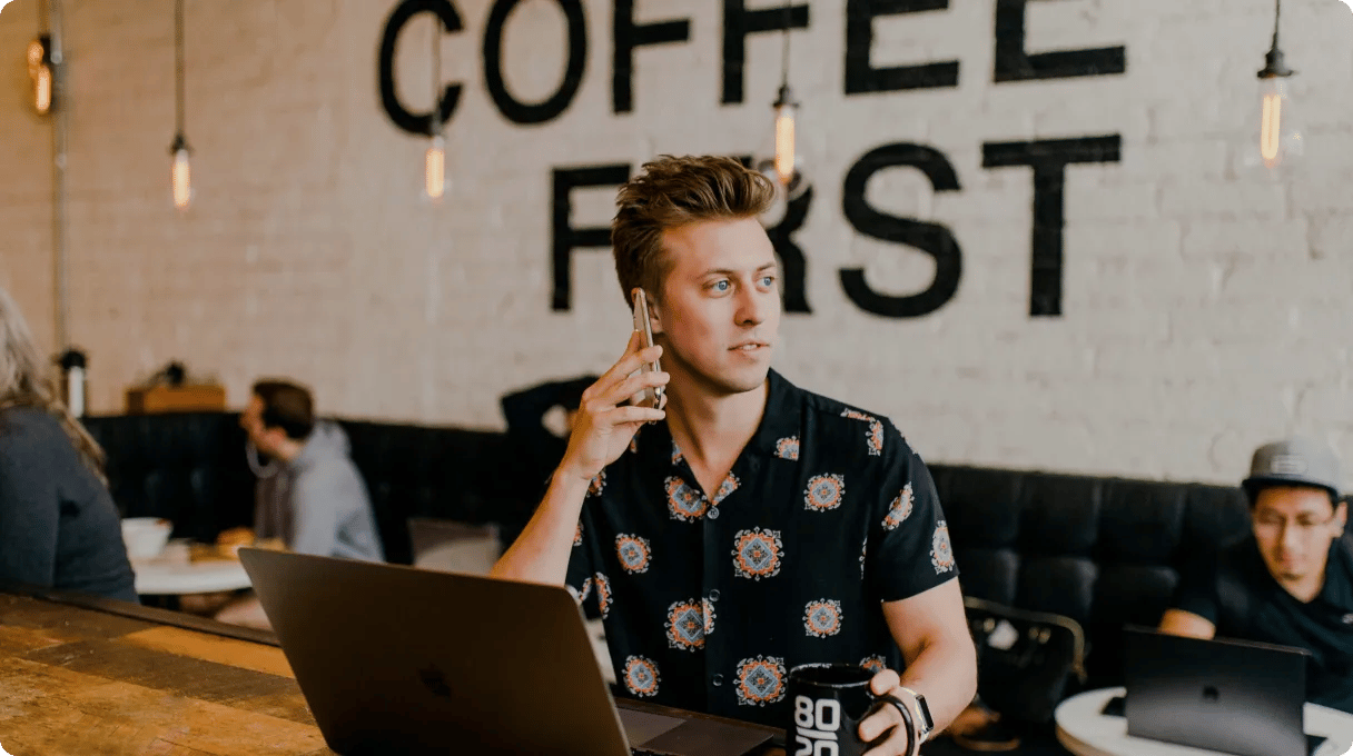 Man On The Phone With Mug In Another Hand