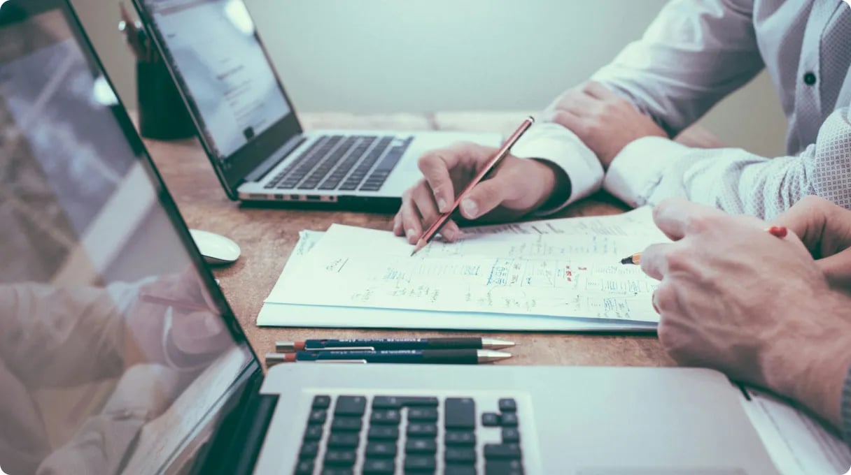 Person Holding Pencil Near Laptop