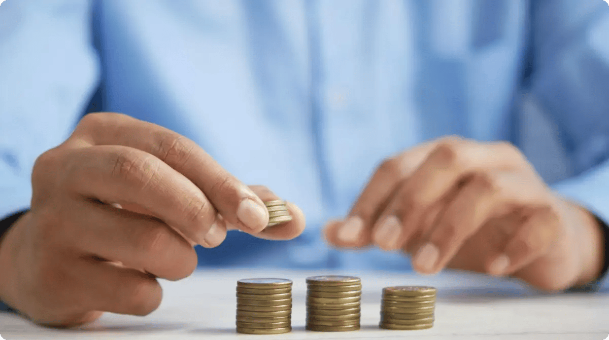 A Person Stacking Coins On Top Of A Table
