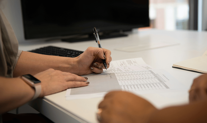 Entrepreneur reviewing a contract at a desk with warning symbols and documents labeled 'Legal Issues' and 'Missed Terms'—representing costly legal mistakes made after reaching $100K in sales.