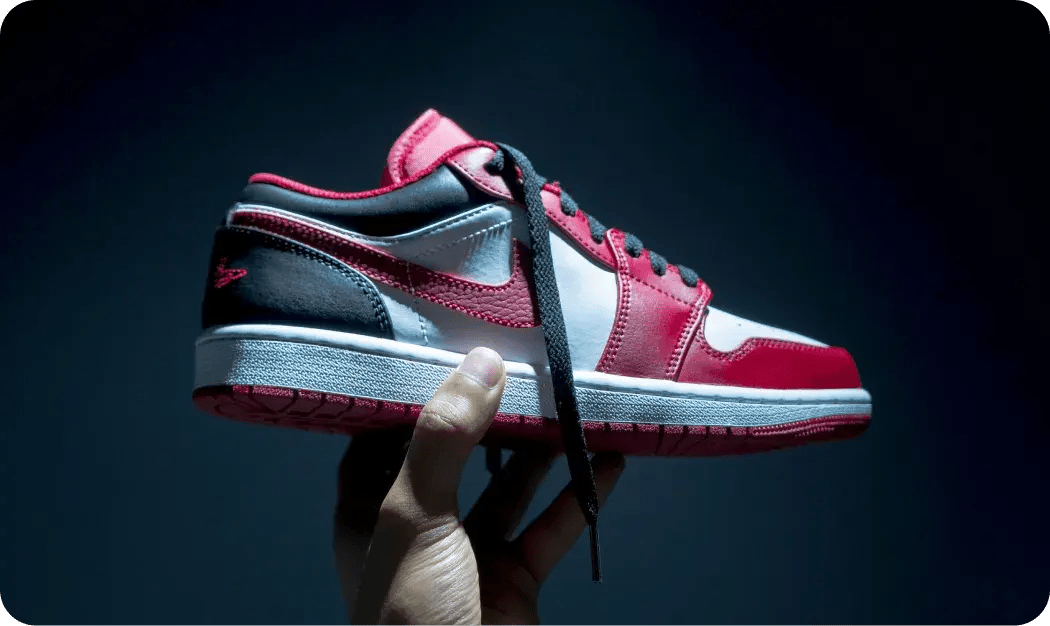 Hand Holding Red And White Sneaker In Dramatic Lighting