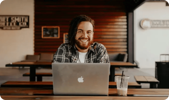 Man Smilling From Hehind Of A Macbook