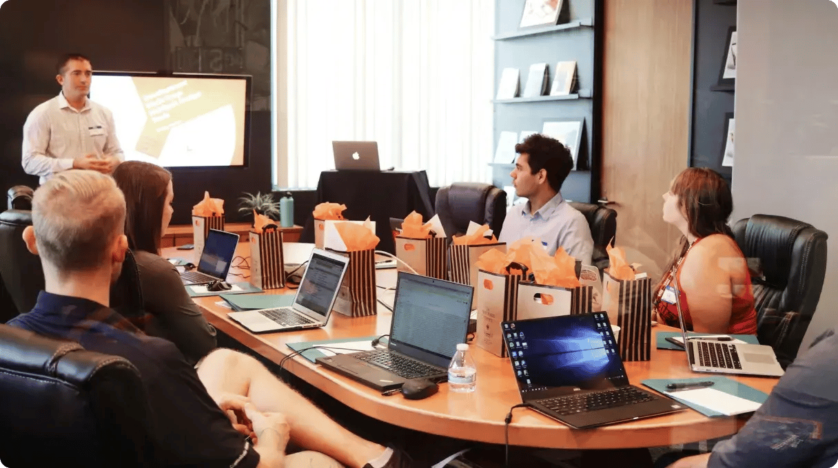 Man Standing In Front Of People Sitting Beside Table With Laptop Computers Gmsnxqiljp4
