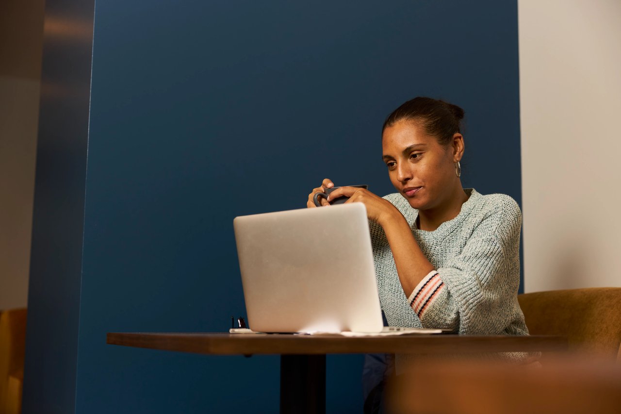 Women holding a pen working on her laptop at cafe.