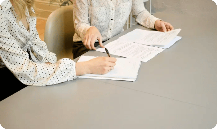 Woman Signing On White Printer Paper Beside Woman About To Touch The Documents Hjckknwcxxq
