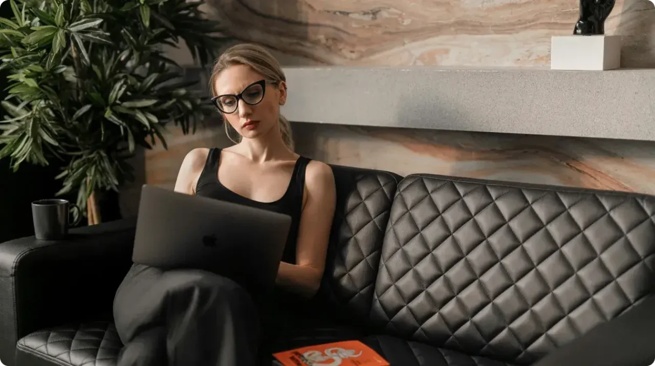Woman Working On Laptop On Sofa At Home