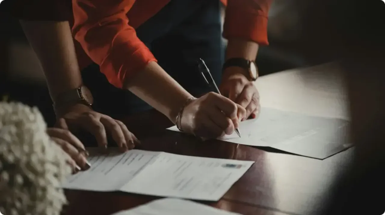 Erson In Orange Long Sleeve Shirt Writing On White Paper